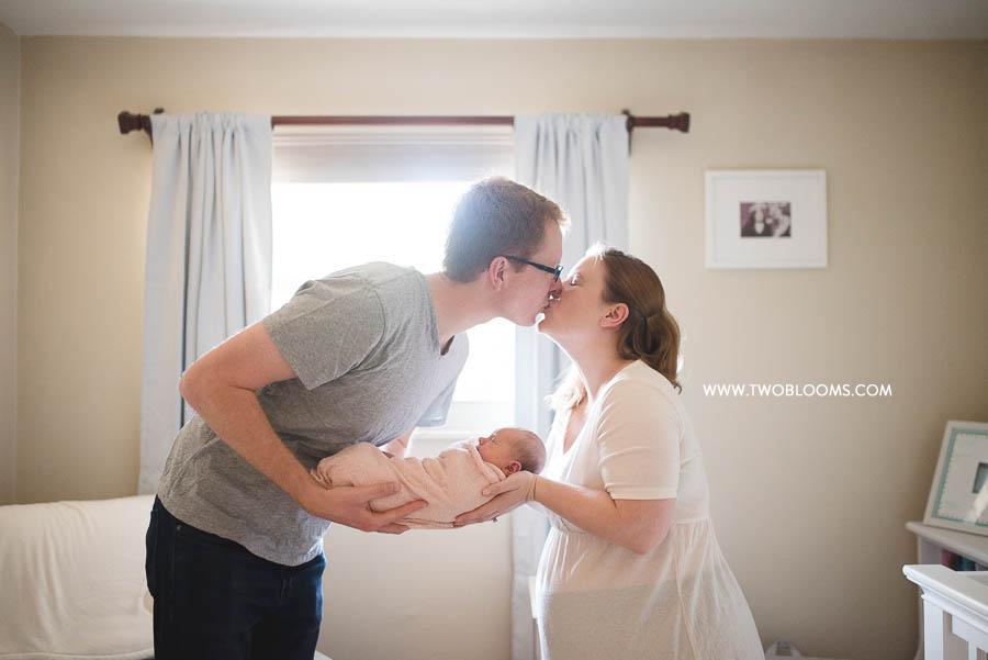 lifestyle newborn photo with Mom and Dad kissing